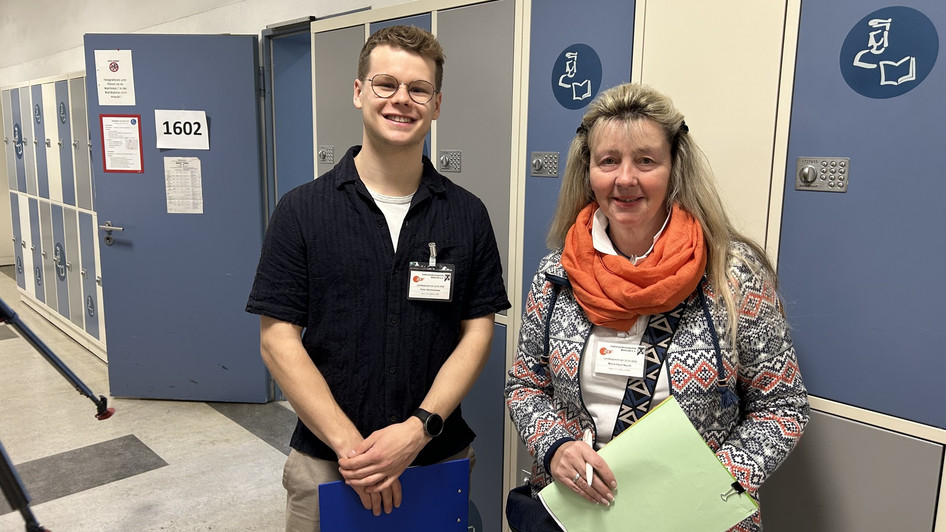 Zwei Mitarbeiter der Forschungsgruppe Wahlen stehen vor einem Wahllokal.