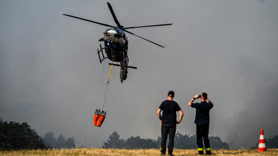 Im Dauereinsatz: Hier belädt ein Hubschrauber der Polizei NRW seine Wassertanks in Großhau auf einem Feld.