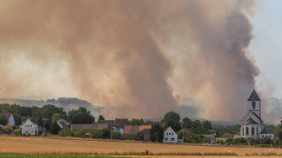 Rauschschwaden verdecken den Wald: Der Brand im Hürtgenwald breitet sich hinter der Ortschaft Birgel mit der Pfarrkirche Sankt Martinus aus.