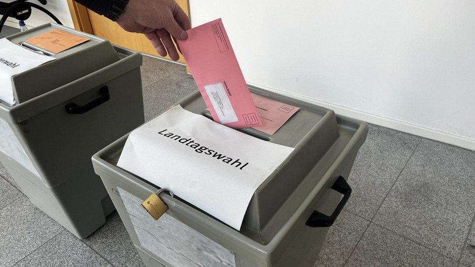 Briefwahlunterlagen werden in eine Wahlurne eingeworfen.